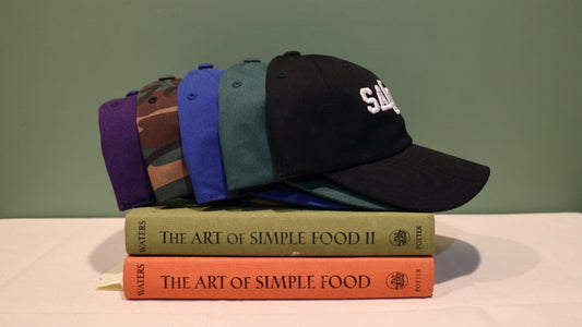 5 colorful caps on a stack of books, 'The Art of Simple Food', with a plain background.
