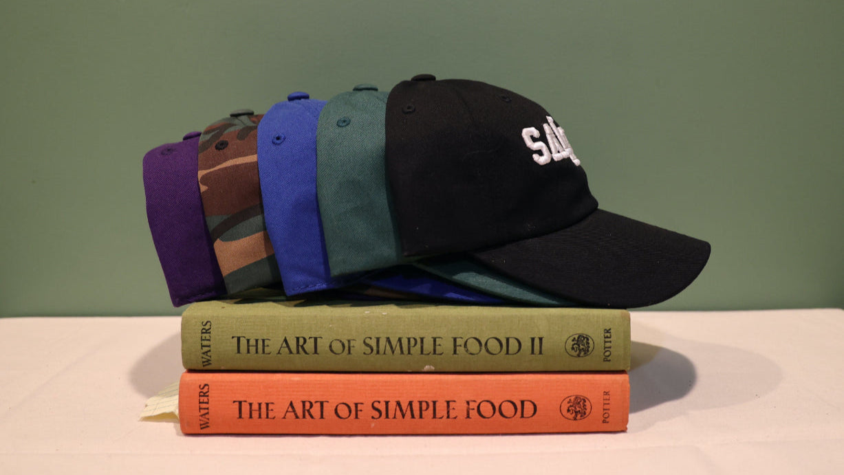 5 colorful caps on a stack of books, 'The Art of Simple Food', with a plain background.