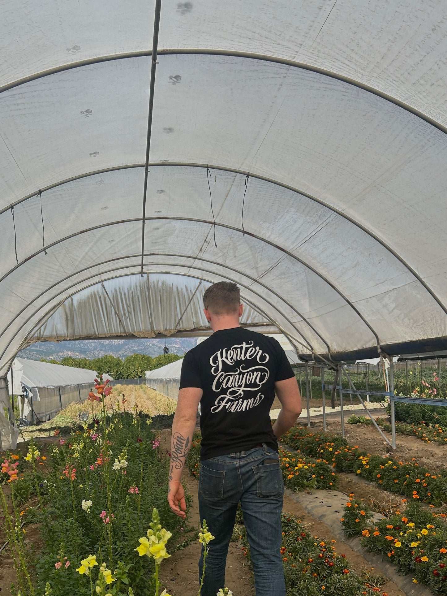 Man walking through a greenhouse with plants and flowers