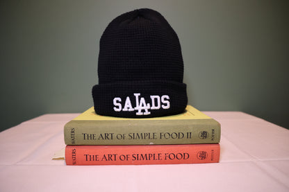 Black beanie with 'SALADS' on top of two books titled 'The Art of Simple Food.' 