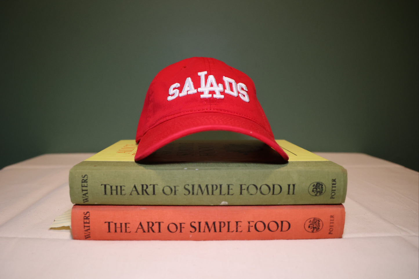 Red cap with 'SALADS' on top of two books titled 'The Art of Simple Food' and 'The Art of Simple Food II'.